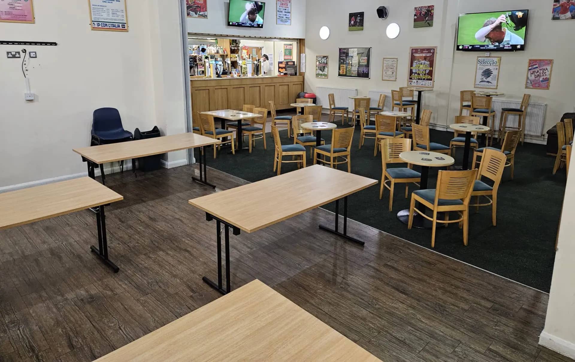 View from the wood-effect function area into the carpeted lounge, with round tables, timber chairs and the bar