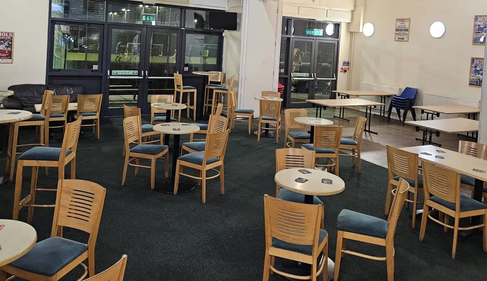Round tables, a sofa and pitch-side glazed doors, with the adjoining function area on the right