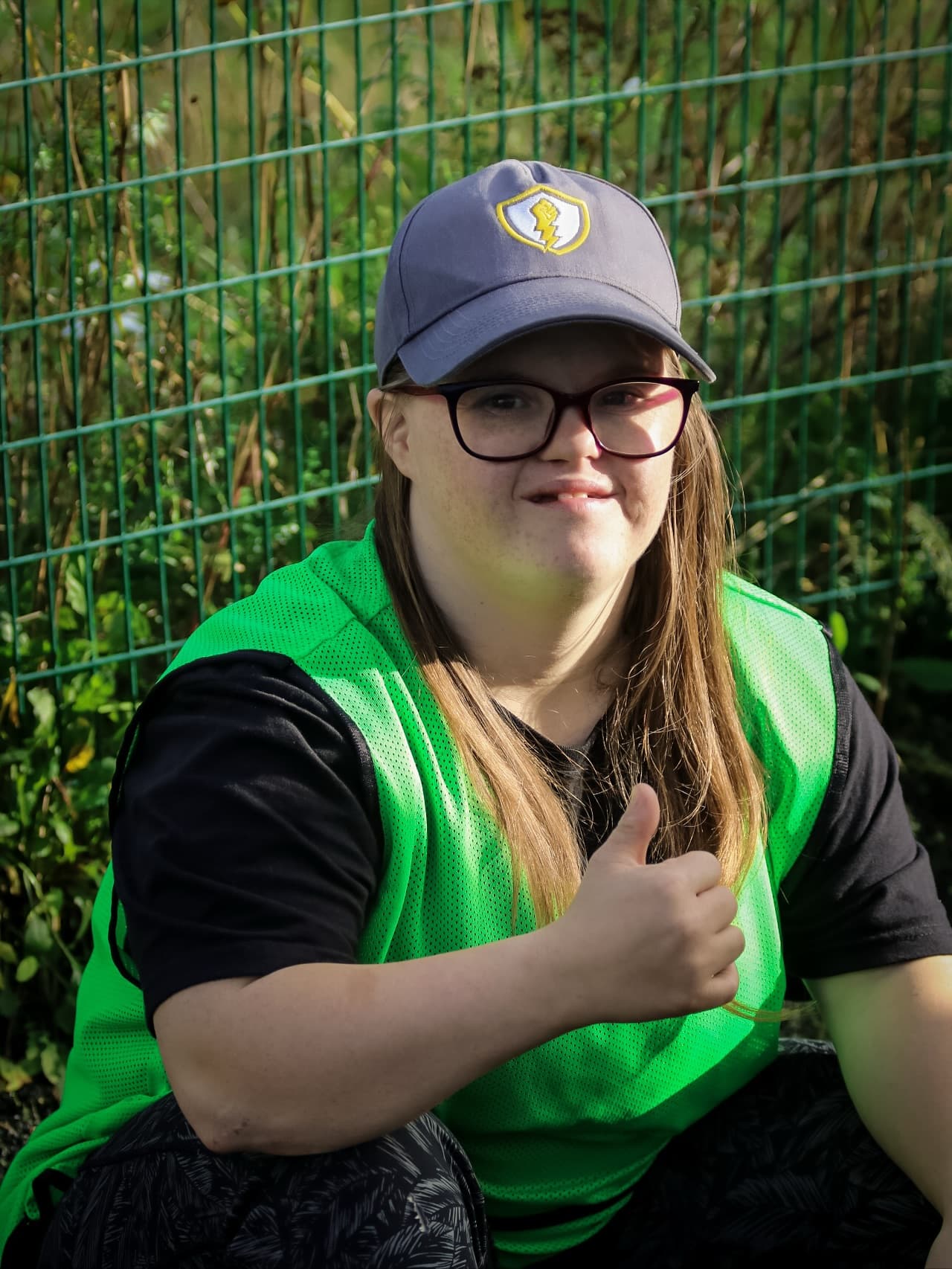 A participant in an SFW cap and bib giving a thumbs up